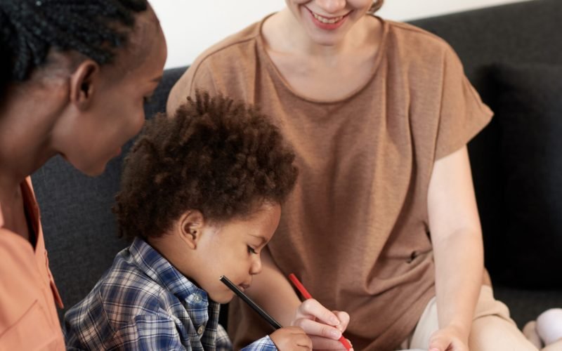 Smiling young women enjoying drawing pictures with toddler son